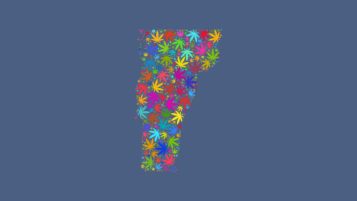 Vermont silhouette made from multicolored cannabis leaves on a muted blue background.