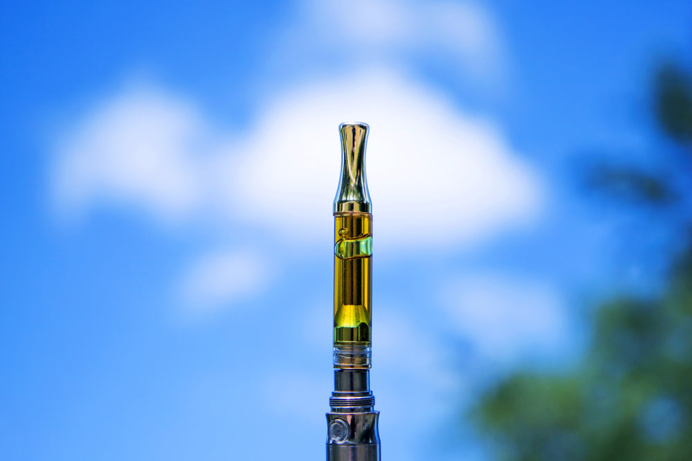 Vape cartridge standing upright against a blue sky